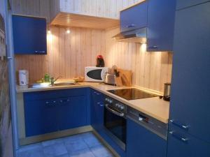 a kitchen with blue cabinets and a microwave at Haubentaucher 80 in Rechlin