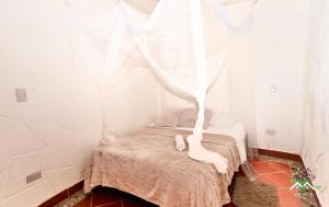 Habitación pequeña con cama con cortinas blancas en Hostal Ariantiy en Pepino