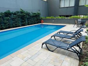 uma piscina com duas espreguiçadeiras ao lado em Hotel - Av Paulista - São Paulo em São Paulo
