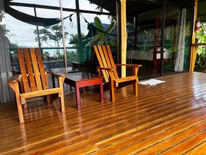 2 chaises et une table sur une terrasse en bois dans l'établissement The Monkey Trail Hostel, à Drake