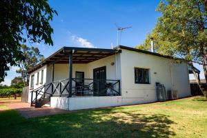 een wit gebouw met een veranda en een grasveld bij Upper Reach Spa Cottage in Henley Brook