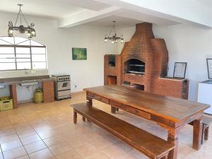 a kitchen with a wooden table and a brick oven at Sítio com vista espetacular in Serra Negra