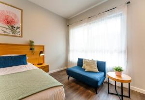 um quarto com uma cama e uma cadeira azul e uma janela em Aberdeen Lane em Woodside