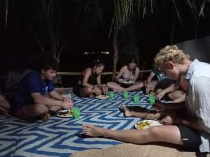 un grupo de hombres sentados en la playa comiendo comida en Lusis Homestay, en Lautoka