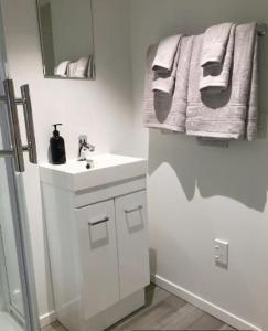 a white bathroom with a sink and a mirror at Kingsland Studio - Walk to Eden Park! in Auckland