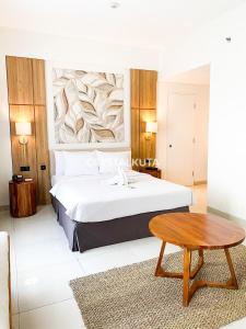 1 dormitorio con 1 cama grande y 1 mesa en Crystalkuta Hotel - Bali en Kuta