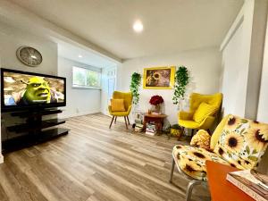 uma sala de estar com uma televisão de ecrã plano e cadeiras amarelas em Private Room with Shared Bathroom on a Lower Level of a Big and Peaceful House em Seattle