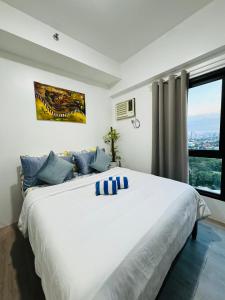 a bedroom with a large white bed with a window at Vinia Infinity Studio 1 Near Malls with WiFi and Netflix in Manila