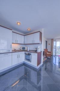 a kitchen with white cabinets and a tile floor at Seeadler 205 in Rechlin +1 photo