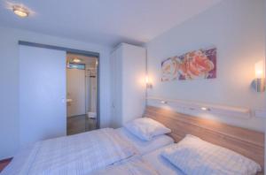 a bedroom with a white bed with a wooden headboard at Seeadler 205 in Rechlin