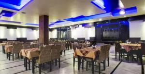 Goroomgo Park Paradise Manali - Elevator Lift & Parking Facilities في مانالي: مطعم فيه طاولات وكراسي في الغرفة