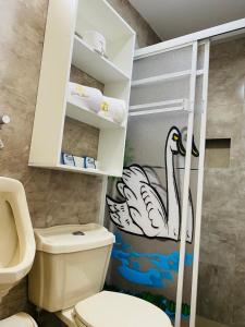 baño con aseo y un cisne pintado en la pared en Casa Gaviota Dorada, en Baños