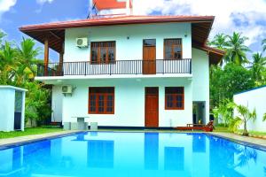 a house with a swimming pool in front of a house at Hannaford House Bentota in Bentota