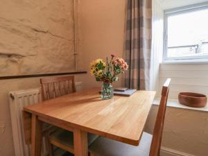 a dining room table with a vase of flowers on it at Abbey View Cottage in Hawsker +12 photos