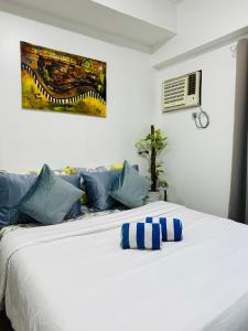 a white bed with blue pillows in a bedroom at Vinia Infinity Studio 1 Near Malls with WiFi and Netflix in Manila