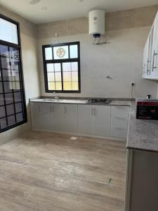 a kitchen with white cabinets and a window at فيلا وشقق السعادة - صلالة in Salalah