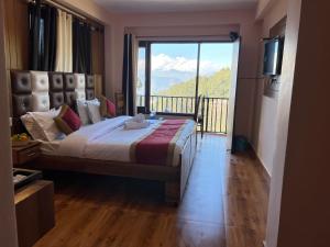 a bedroom with a large bed and a balcony at Hotel Canadian forest view in Dalhousie