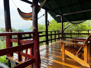 eine Holzterrasse mit einer Hängematte darüber in der Unterkunft Nativos Corcovado cabins in Drake