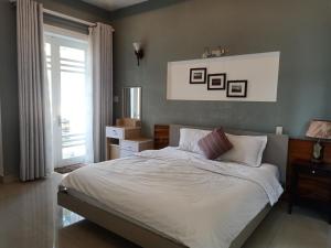 a bedroom with a bed with white sheets and a window at Rose's House Hue in Hue