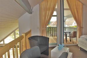 a living room with a balcony with a couch and chairs at Seeschwalbe Classic 77 in Rechlin