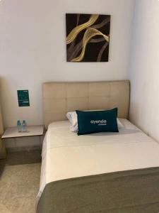 a bed with a blue pillow on top of it at Hotel boutique San Pablo in Medellín
