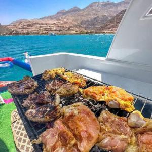 einen Grill mit Fleisch und anderen Speisen auf einem Boot in der Unterkunft بورتو السخنه ترحب بكم - Aprag Porto Alsokhna in Suez