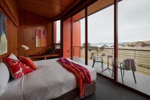 Iron Creek Bay Estate في Sorell: غرفة نوم بها سرير وبلكونة بها نوافذ