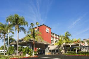 ein rotes Gebäude mit Palmen davor in der Unterkunft ALO Hotel by Ayres, Orange in Anaheim