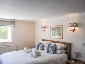 1 dormitorio con 1 cama con sábanas y almohadas blancas en Orchard Barn en Salcombe