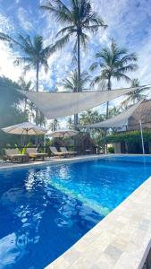uma piscina azul com palmeiras ao fundo em Vyaana Resort Gili Air em Gili Air