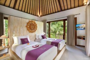 two beds in a room with a tv at Dedary Resort Ubud by Ini Vie Hospitality in Ubud