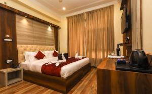 um quarto de hotel com uma cama e uma televisão em Hotel Grand Nest em Dharamshala