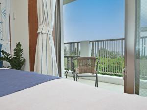 a bedroom with a bed and a balcony at Churaumi Terrace in Motobu