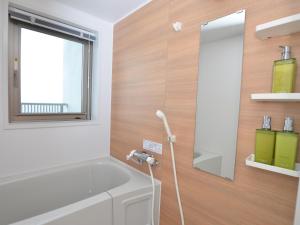 a bathroom with a tub and a sink and a mirror at Churaumi Terrace in Motobu