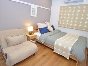 a small bedroom with a bed and a chair at Churaumi Terrace in Motobu
