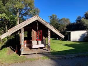 cenador de madera con sofá en el césped en Kiwi cabin with geothermal pool by lake Taupo en Turangi