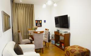 sala de estar con TV, mesa y sillas en APARTAMENTOS COMPLETOS Cama Queen a 10 min Aeropuerto Lima Per, en Lima