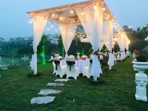Ivory Villa & Resort في Hòa Bình: صف من الطاولات والكراسي تحت خيمة بها انارة