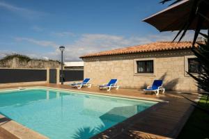 ein Pool mit blauen Stühlen und ein Haus in der Unterkunft Logement avec baignoire SPA Villa de luxe in Fonte Boa