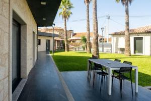 einen Tisch und Stühle auf einer Terrasse mit Palmen in der Unterkunft Logement avec baignoire SPA Villa de luxe in Fonte Boa