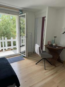 1 dormitorio con escritorio, silla y ventana en 2 chambres adjacentes dans villa avec jardin de pins en Commugny