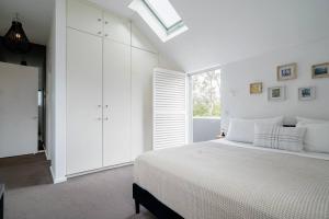 a white bedroom with a bed and a window at Sydney Penthouse in Sydney