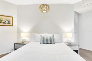 ein weißes Schlafzimmer mit einem großen weißen Bett mit zwei Lampen in der Unterkunft Lotus Lakes - Resort Style Living in Cairns North + 9 Fotos