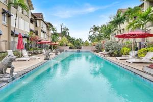 una piscina in un resort con sedie e ombrelloni di Lotus Lakes - Resort Style Living a Cairns North