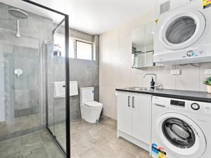 ein Badezimmer mit Waschmaschine und Dusche in der Unterkunft Hectorville Luxe Haven Suite in Campbelltown