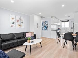 ein Wohnzimmer mit einer schwarzen Couch und einem Tisch in der Unterkunft Hectorville Luxe Haven Suite in Campbelltown