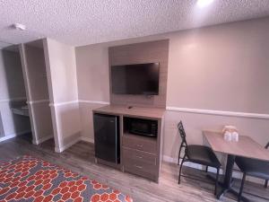 uma sala de estar com uma televisão de ecrã plano e uma mesa em Economy Inn em San Bernardino