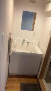 uma casa de banho branca com um lavatório e um espelho em WEST in em Yufu