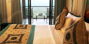 a bedroom with a bed with a view of a balcony at Randholee Resort & Spa in Kandy