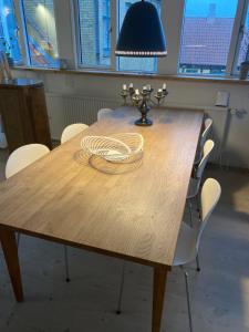 een houten tafel met witte stoelen en een lamp erop bij Ebeltoft in Ebeltoft